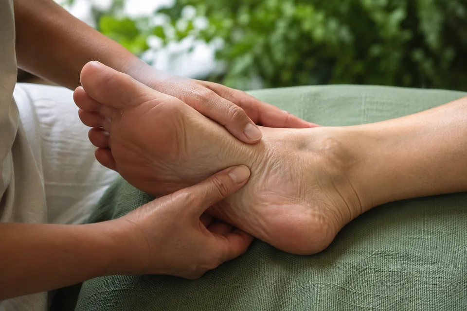 Hands supporting a foot during a quiet reflexology session.