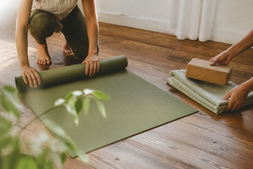 A yoga mat, block and folded blanket being prepared for class.