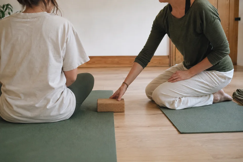 Two people seated on yoga mats during individual guidance.