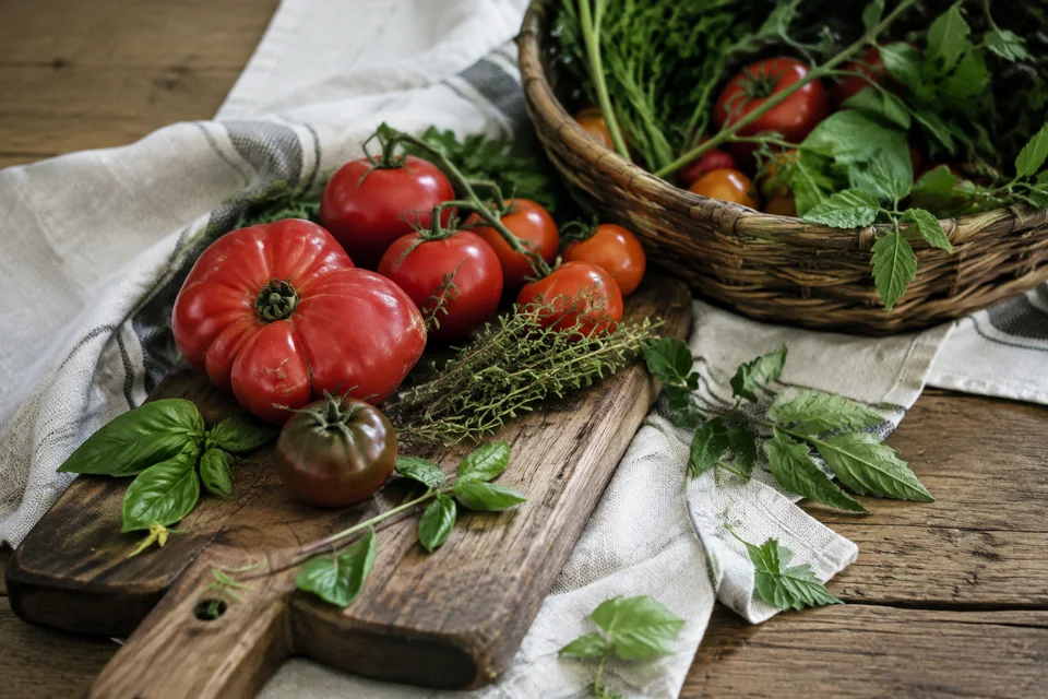 Fresh tomatoes and herbs gathered on linen and a wooden board.
